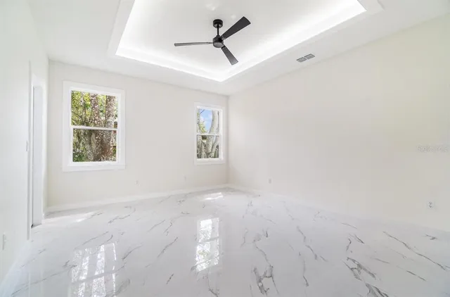 an empty room with windows and fan