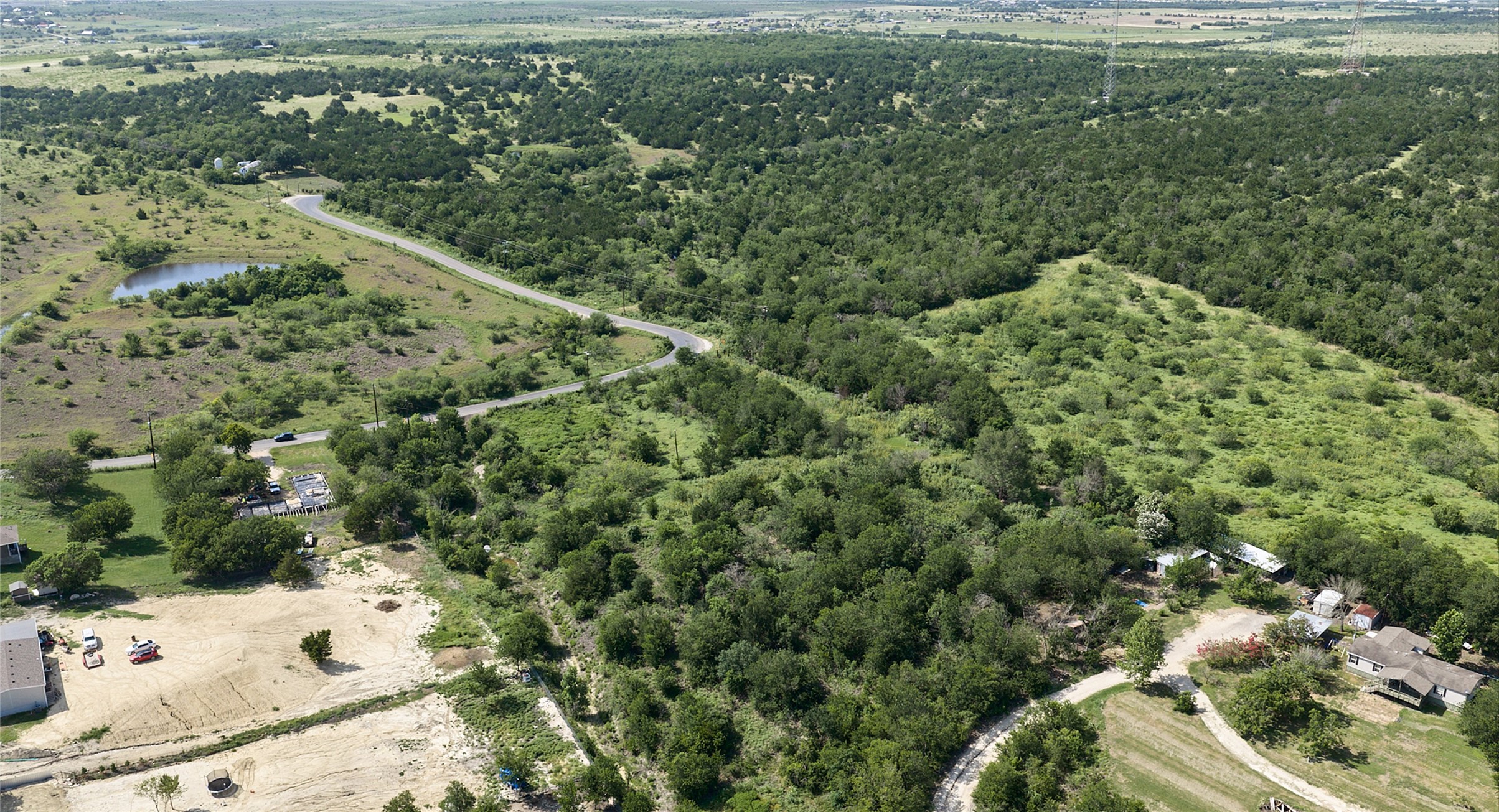 1400 Williamson Road Kyle, TX 78640 - Photo 8 of 13 Discover vast, undeveloped land featuring verdant woodlands, a tranquil pond, and winding roadways.