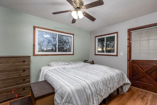 a view of an empty room with wooden floor and a ceiling fan