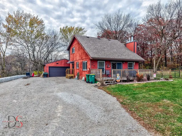 a view of a house with table and chairs under a large tree