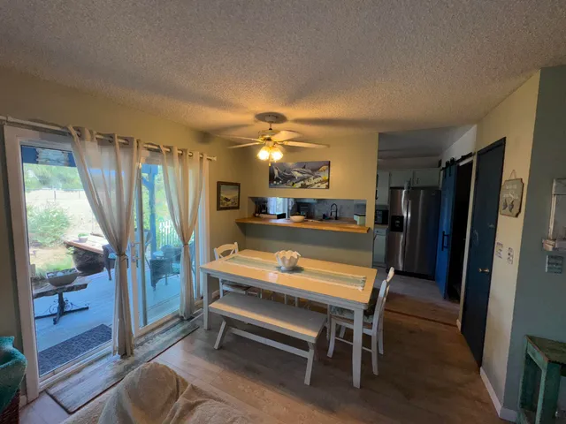 a dining table sitting next to a white wall with kitchen view