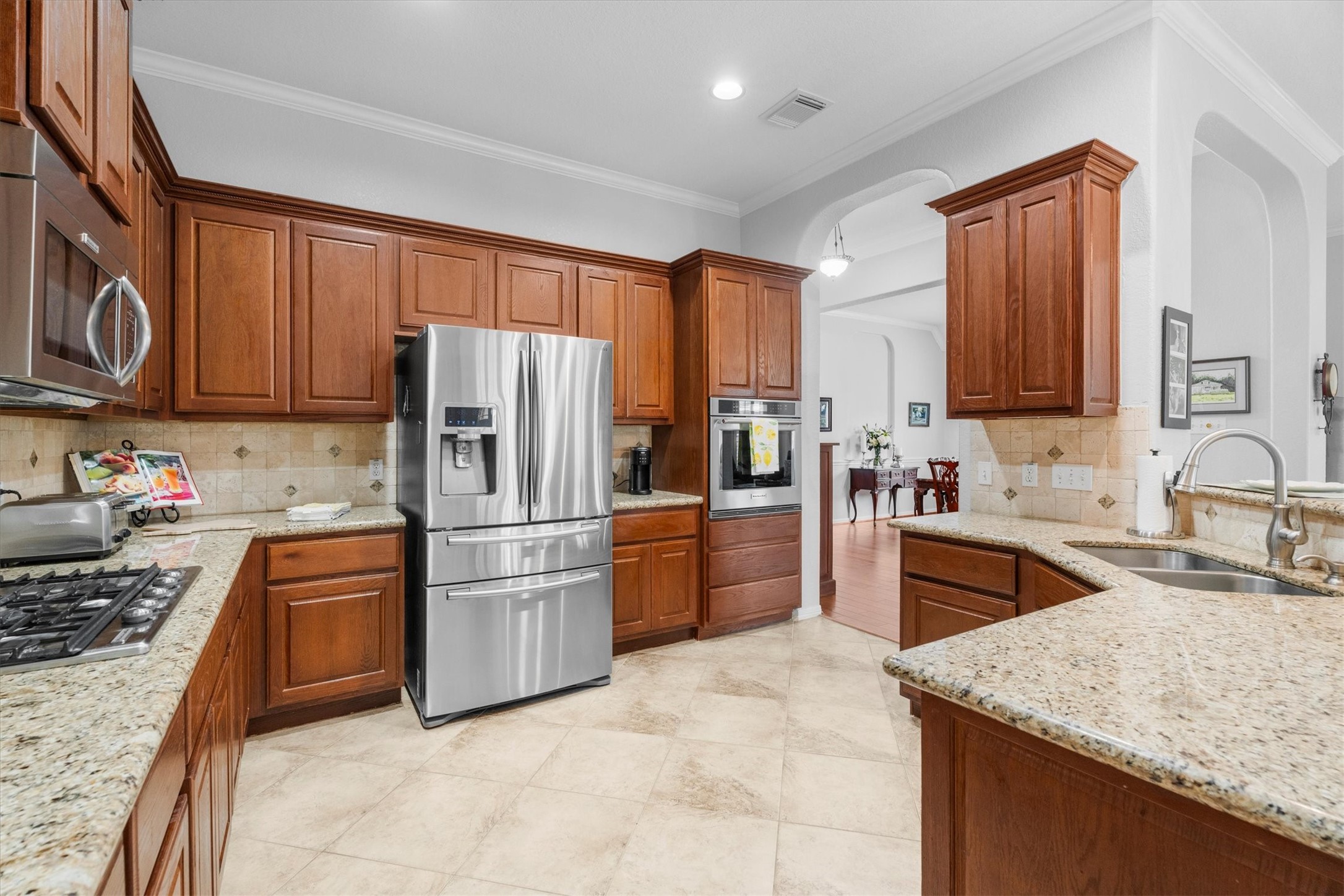 9406 Lochflora Drive Spring, TX 77379 - Photo 15 of 49 a kitchen with granite countertop stainless steel appliances and wooden cabinets