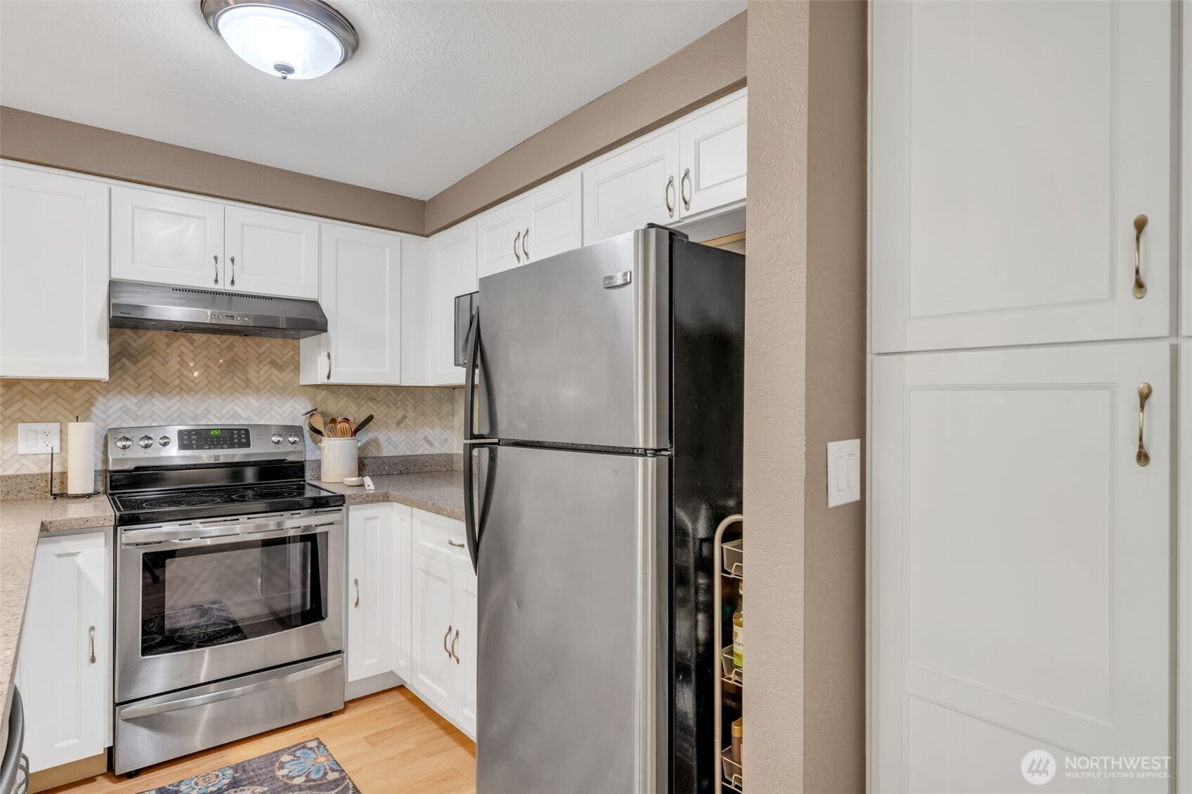 4231 Northeast 5th Street, Unit E101 Renton, WA 98059 - Photo 11 of 29 a kitchen with stainless steel appliances a refrigerator a stove and white cabinets