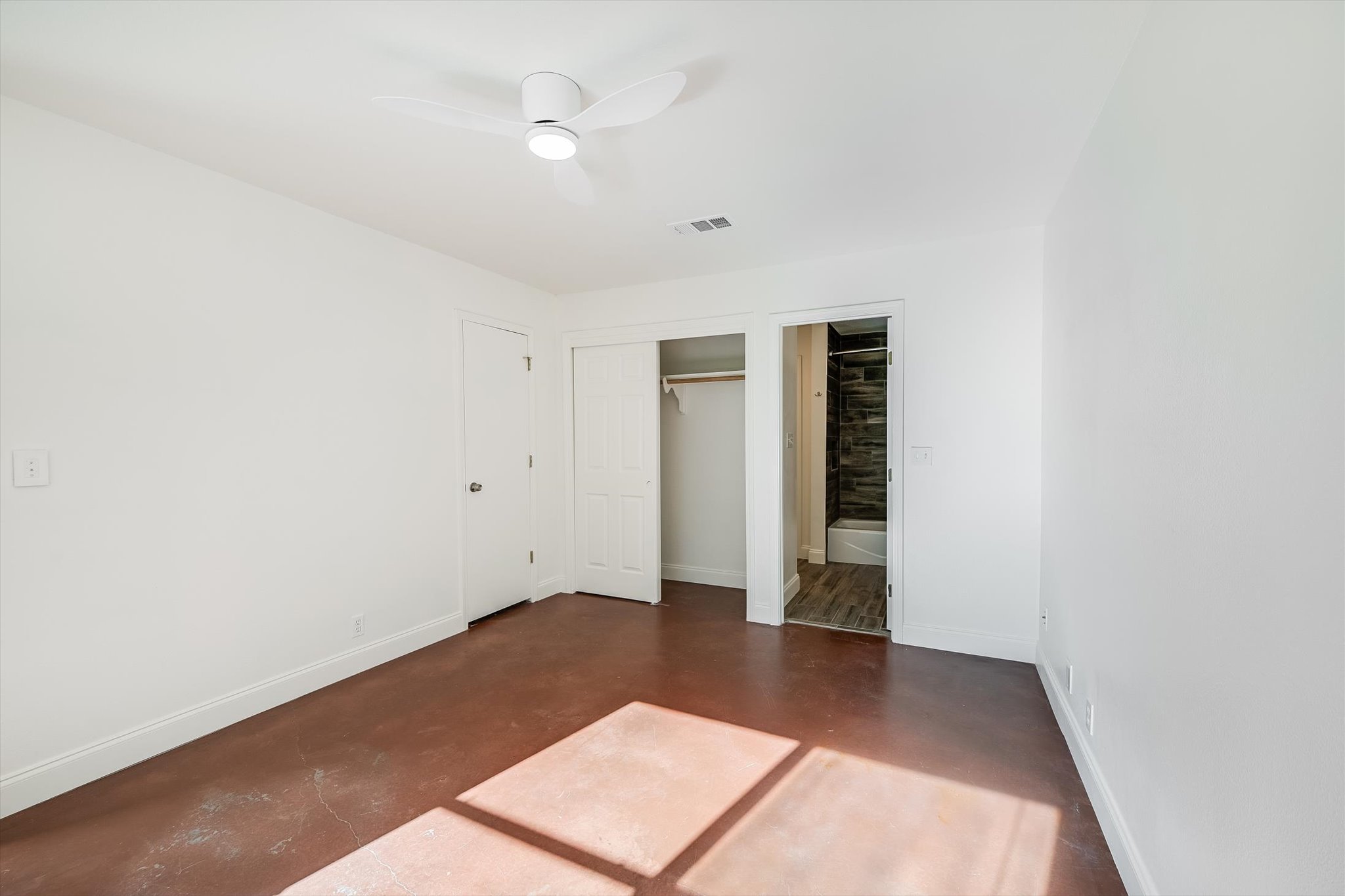 302 Lago Verde Road Lakeway, TX 78734 - Photo 14 of 21 Unfurnished bedroom with finished concrete floors, a closet, connected bathroom, and ceiling fan