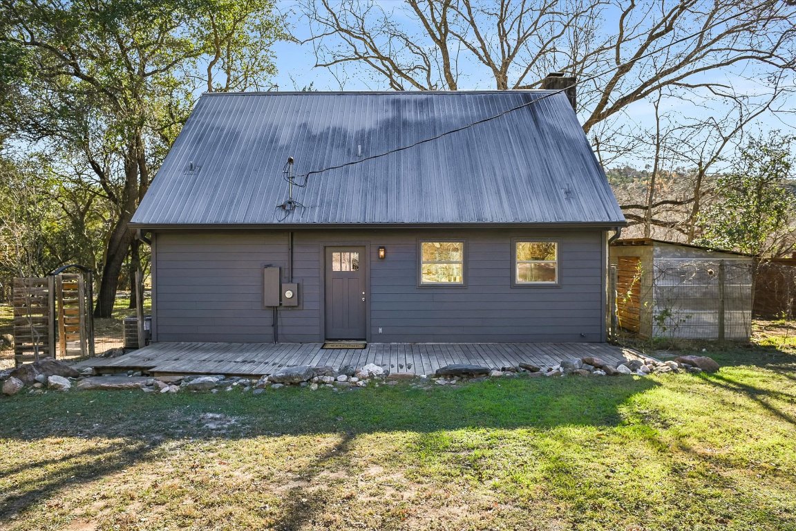 302 Lago Verde Road Lakeway, TX 78734 - Photo 16 of 21 Back of house featuring a chimney, a metal roof, a wooden deck, and an outdoor structure