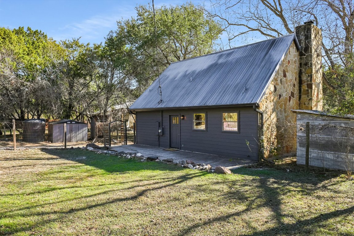 302 Lago Verde Road Lakeway, TX 78734 - Photo 17 of 21 Rear view of property featuring an outbuilding, a metal roof, a chimney, stone siding, and a deck