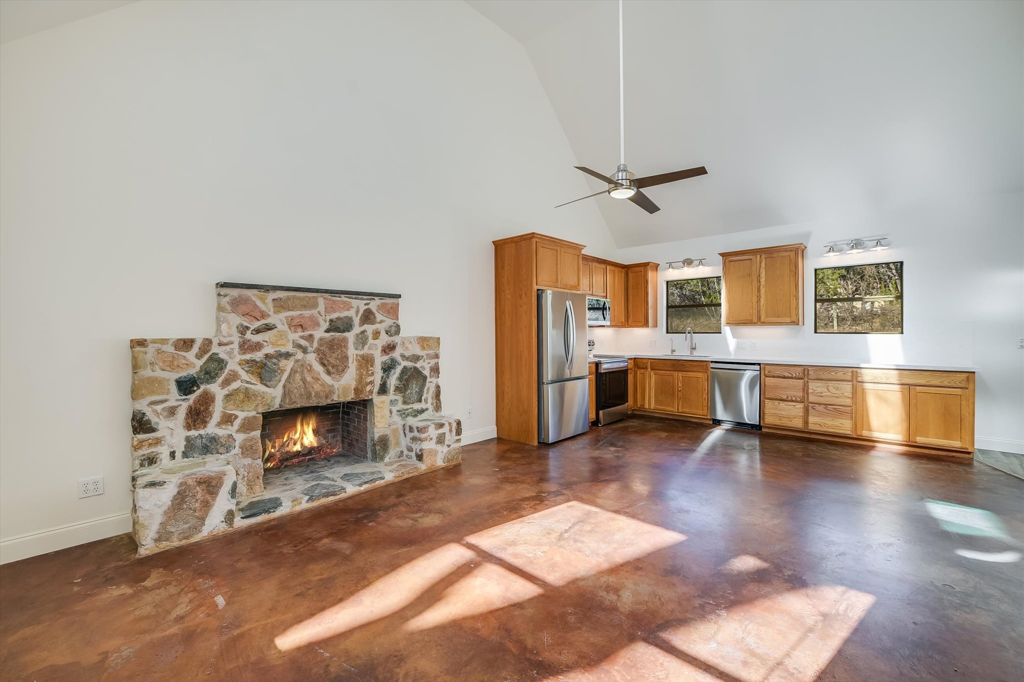 302 Lago Verde Road Lakeway, TX 78734 - Photo 5 of 21 Kitchen with a stone fireplace, stainless steel appliances, finished concrete floors, high vaulted ceiling, and ceiling fan