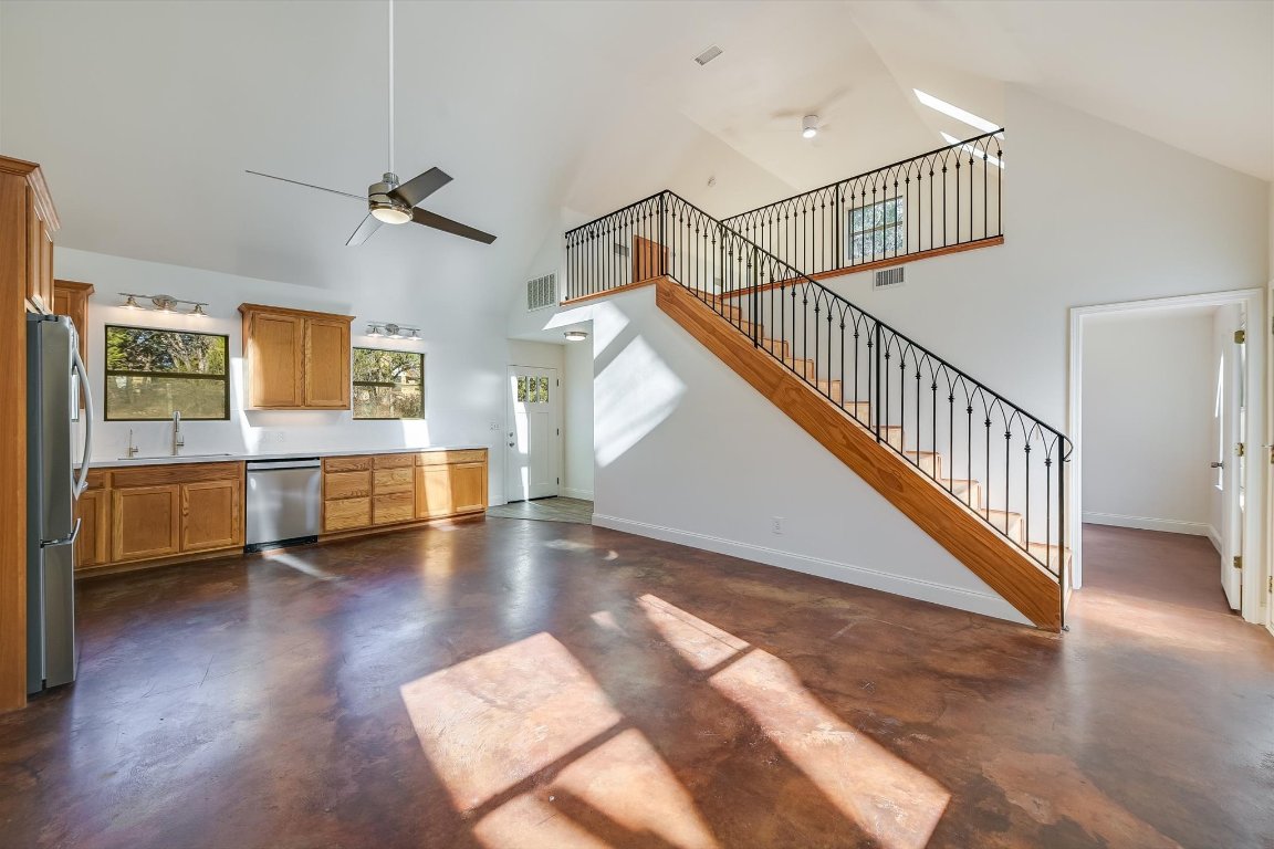 302 Lago Verde Road Lakeway, TX 78734 - Photo 6 of 21 Unfurnished living room with a ceiling fan, finished concrete flooring, high vaulted ceiling, and stairway
