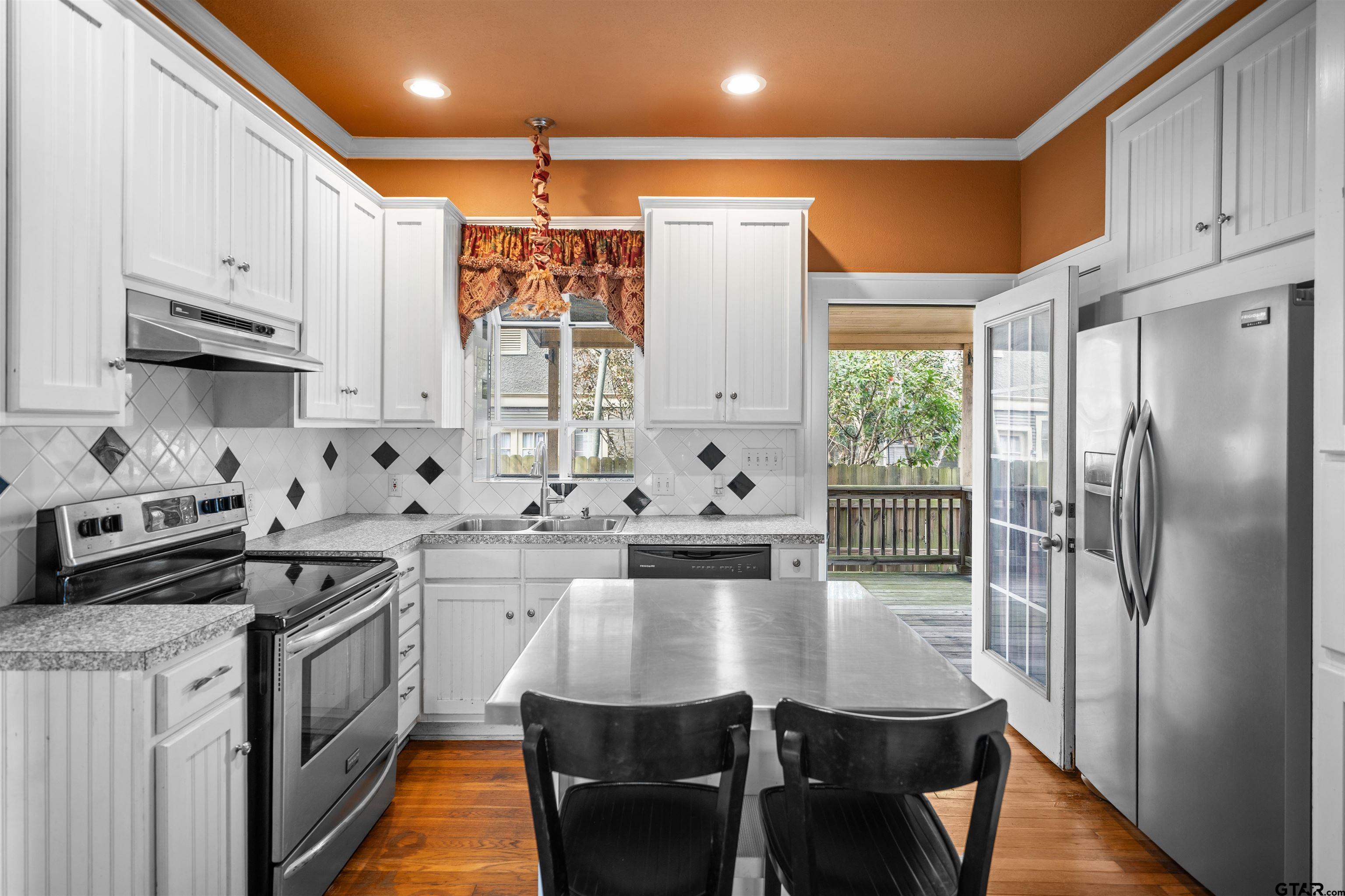 315 Mockingbird Lane Tyler, TX 75701 - Photo 11 of 33 a kitchen with stainless steel appliances granite countertop a stove a sink dishwasher a refrigerator white cabinets and wooden floor