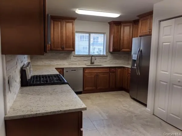 a kitchen with stainless steel appliances granite countertop a sink stove refrigerator and cabinets