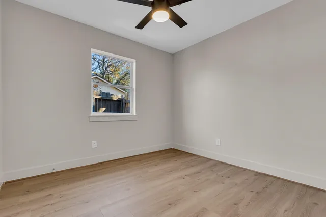 an empty room with a window and a ceiling fan