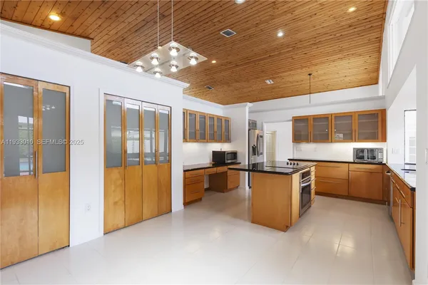 a large room with kitchen island wooden floor and stainless steel appliances
