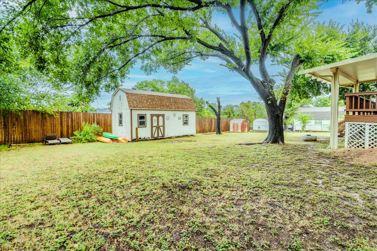 104 Clear Springs Road Georgetown, TX 78628 - Photo 26 of 30 A spacious backyard features a charming shed, ample greenery, and a covered deck for outdoor enjoyment.