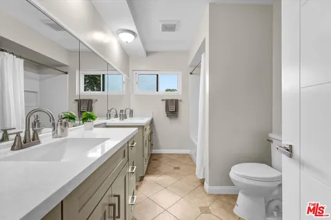 a bathroom with a granite countertop sink mirror vanity and toilet