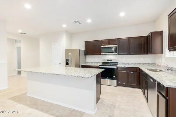 a kitchen with granite countertop a refrigerator and a stove top oven