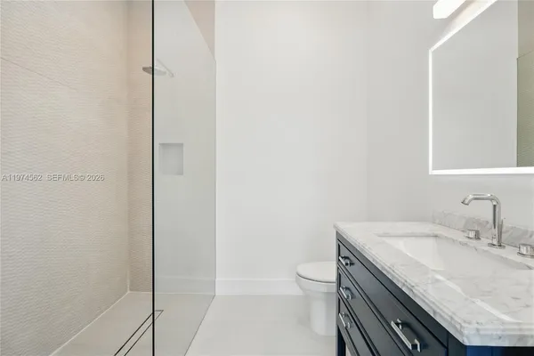 a bathroom with a granite countertop sink a toilet and a shower