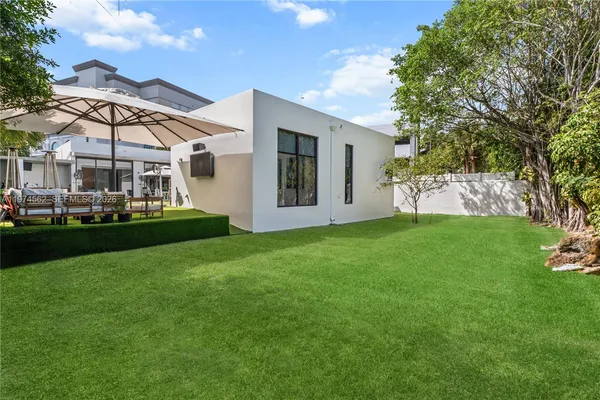 a view of a house with a big yard and large trees