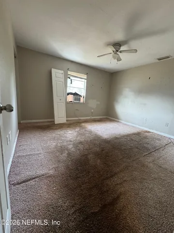 en empty room with windows and ceiling fan