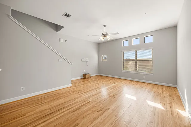 a view of empty room with wooden floor and fan