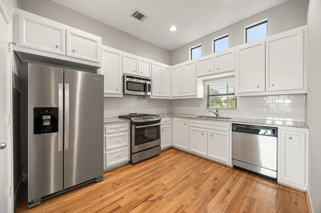 a kitchen with granite countertop white cabinets and stainless steel appliances