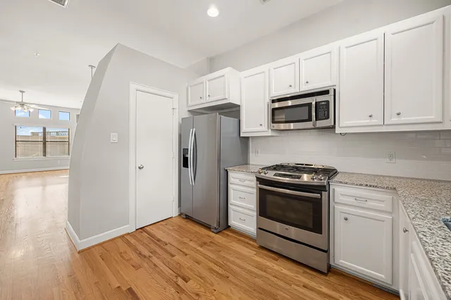 a kitchen with granite countertop white cabinets and stainless steel appliances
