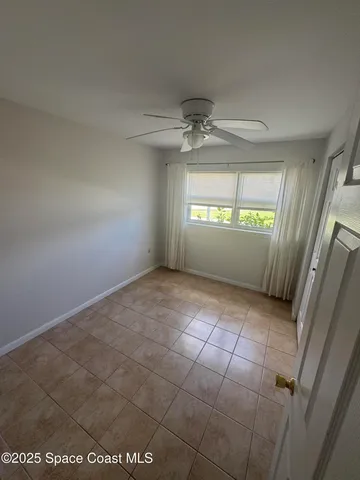 a view of a refrigerator in kitchen and an empty room in wooden floor