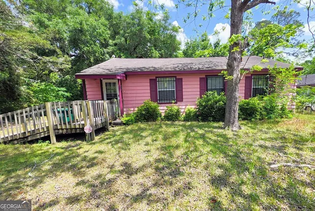 a view of a yard in front of a house with plants and large tree