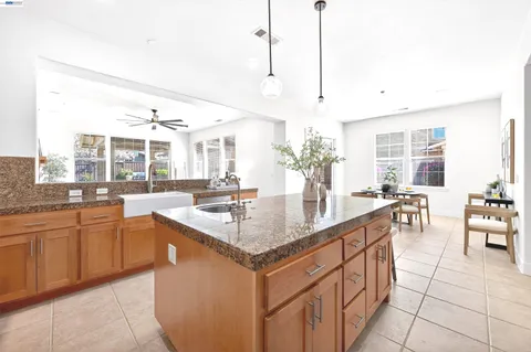 a dining room with stainless steel appliances kitchen island granite countertop a refrigerator a oven a sink with a dining table and chairs