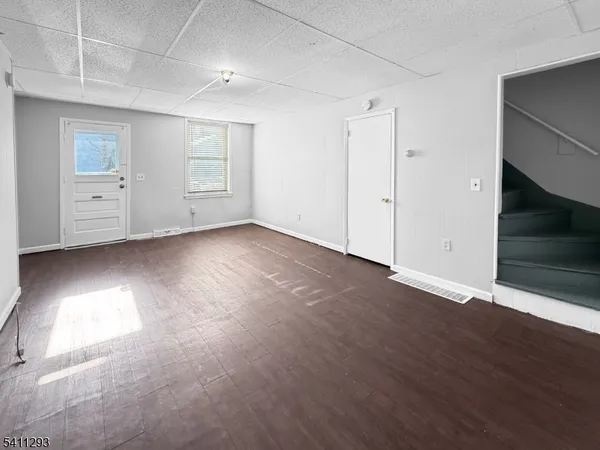 an empty room with wooden floor cabinet and windows