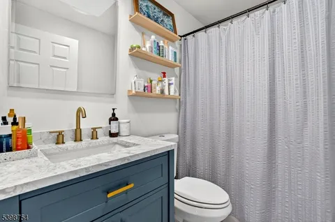 a bathroom with a granite countertop sink vanity mirror and toilet