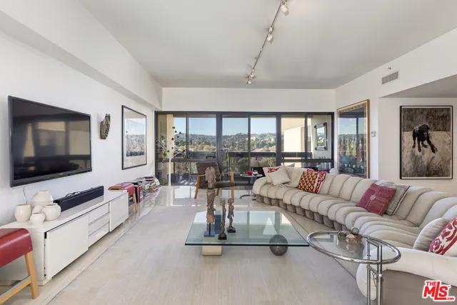a living room with furniture kitchen view and a flat screen tv