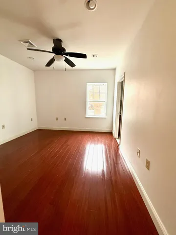 an empty room with wooden floor a ceiling fan and windows
