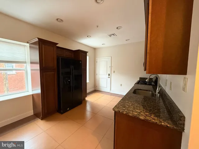 a kitchen with granite countertop a refrigerator and a stove top oven