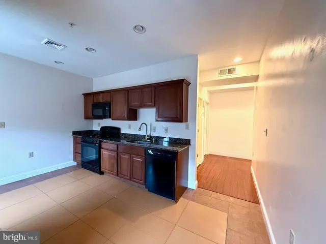 a large kitchen with stainless steel appliances granite countertop a refrigerator and a stove top oven