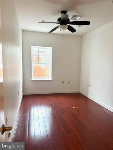 an empty room with wooden floor cabinet and windows