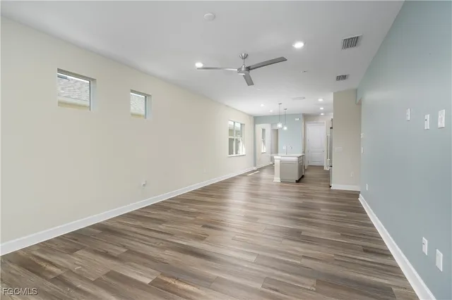 a view of an empty room with wooden floor and a ceiling fan