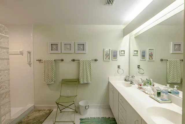 a spacious bathroom with a double vanity sink a mirror and shower