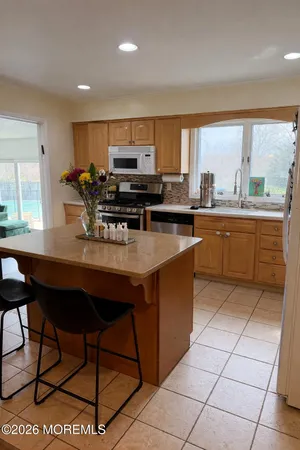 a kitchen with stainless steel appliances granite countertop a table chairs and a refrigerator