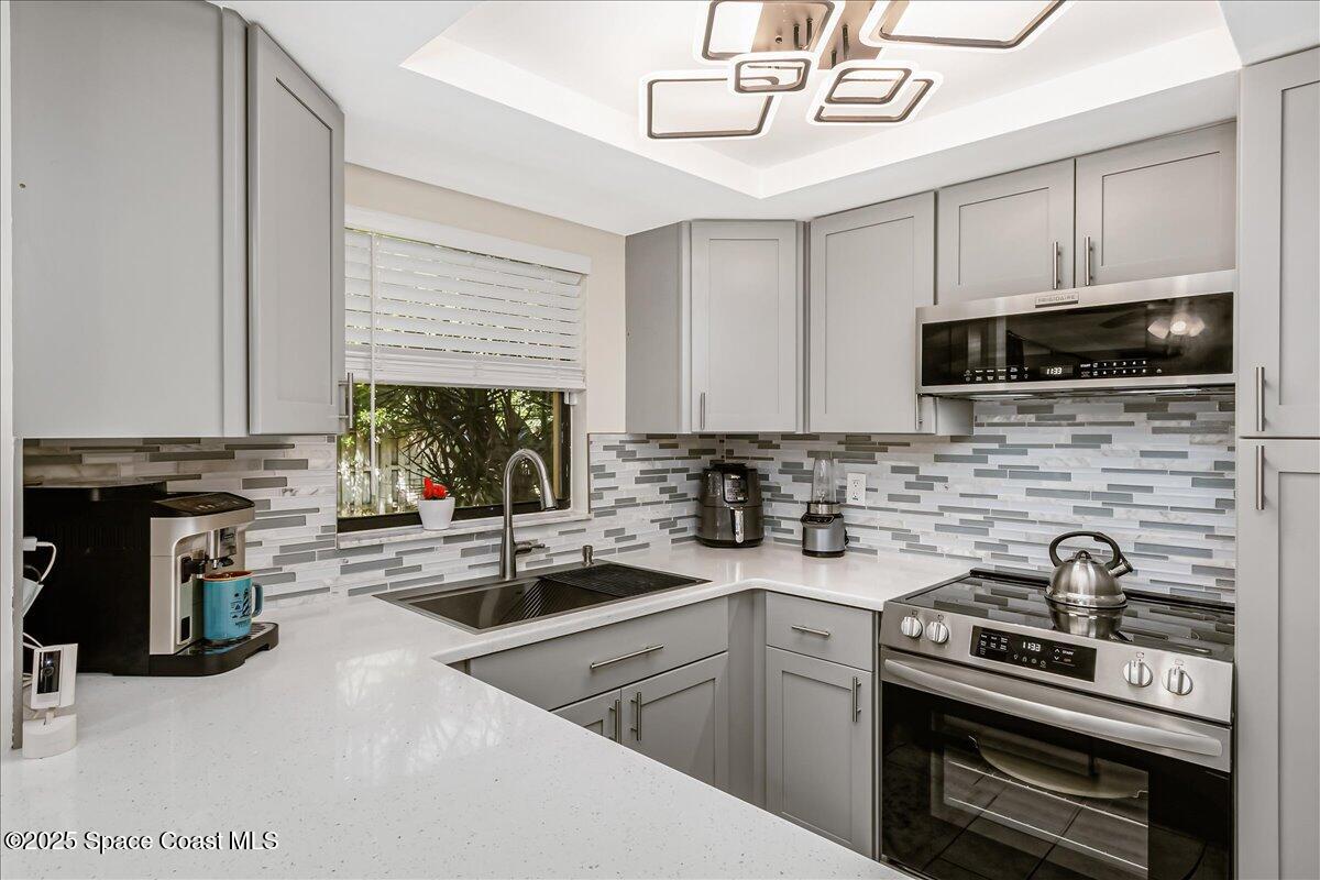 586 North Wickham Road, Unit 63 Melbourne, FL 32935 - Photo 13 of 83 a kitchen with stainless steel appliances a stove sink microwave and cabinets