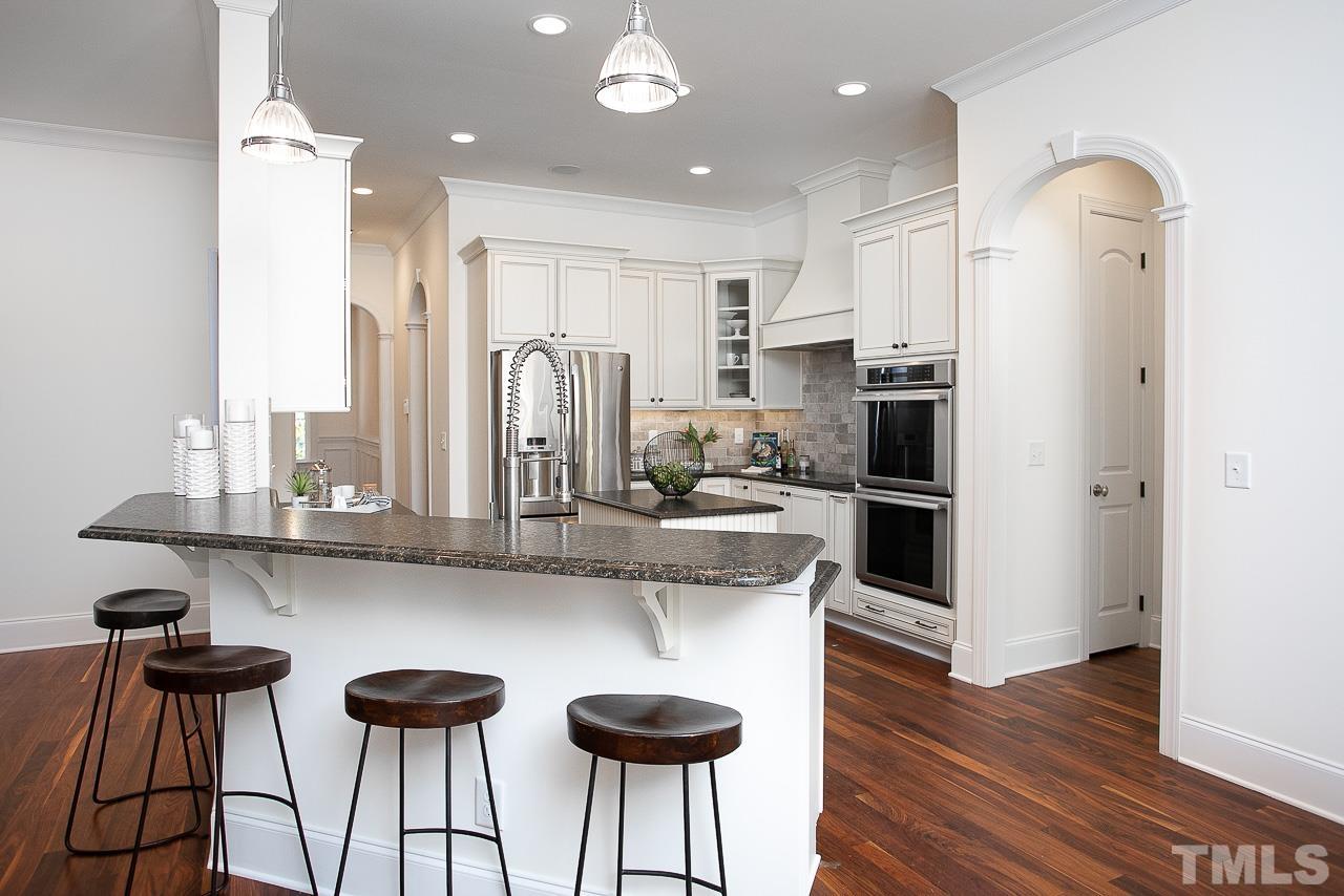 8087 Wake Road Durham, NC 27713 - Photo 11 of 30 a kitchen with stainless steel appliances kitchen island a refrigerator and wooden floor