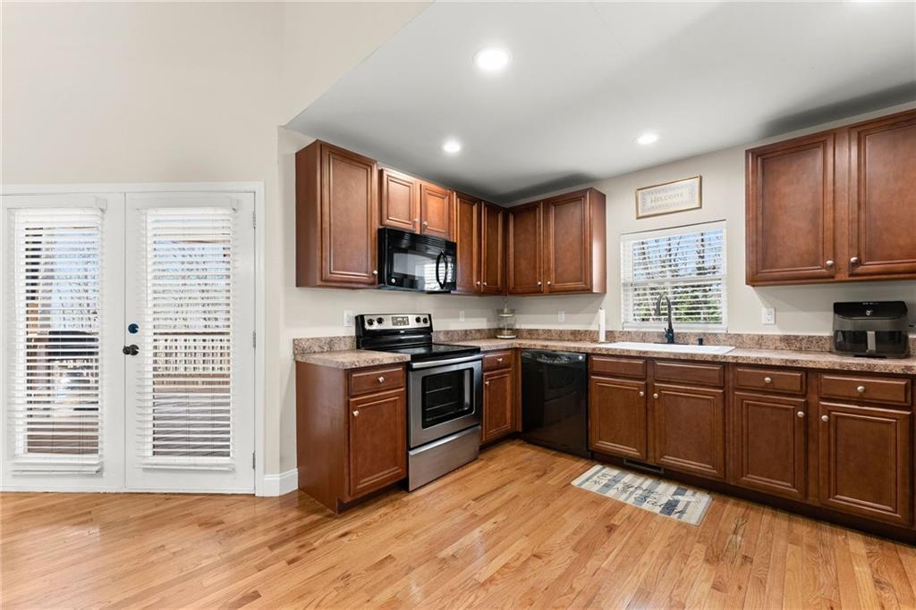 3211 The Trail Road Gainesville, GA 30501 - Photo 10 of 35 a kitchen with stainless steel appliances granite countertop wooden floors a stove a microwave a sink and a window