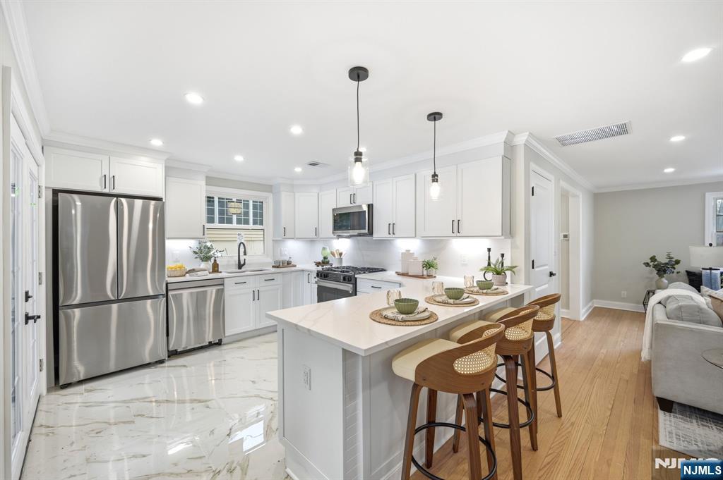 30 West Lawn Road Livingston, NJ 07039 - Photo 7 of 33 a kitchen with stainless steel appliances kitchen island granite countertop a dining table chairs and a refrigerator