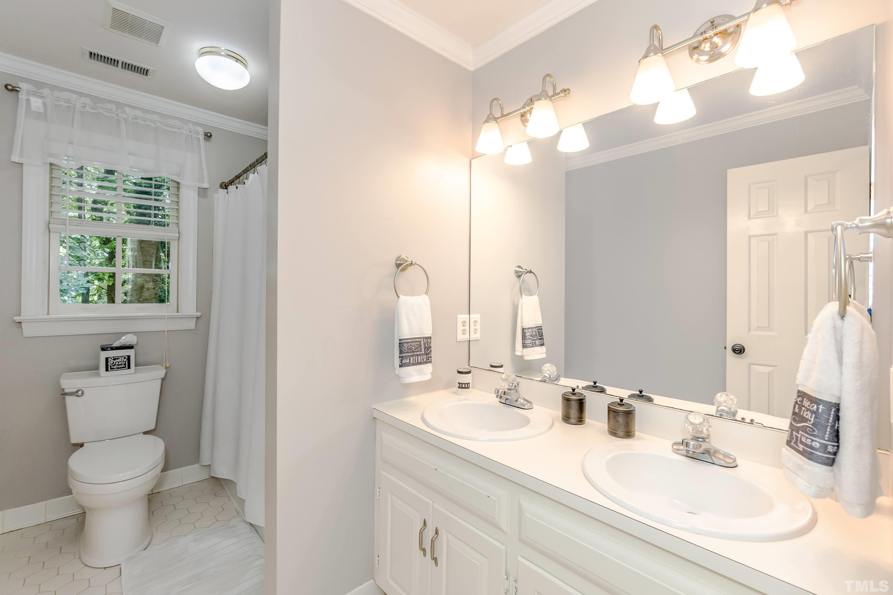 7904 Sandy Bottom Way Raleigh, NC 27613 - Photo 22 of 30 a bathroom with a toilet a sink a large mirror and vanity