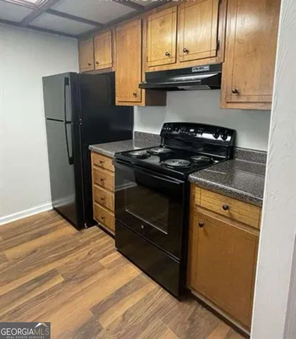 a kitchen with granite countertop a refrigerator stove and cabinets