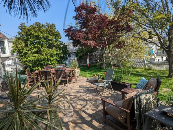 a view of a patio with table and chairs and potted plants and large trees