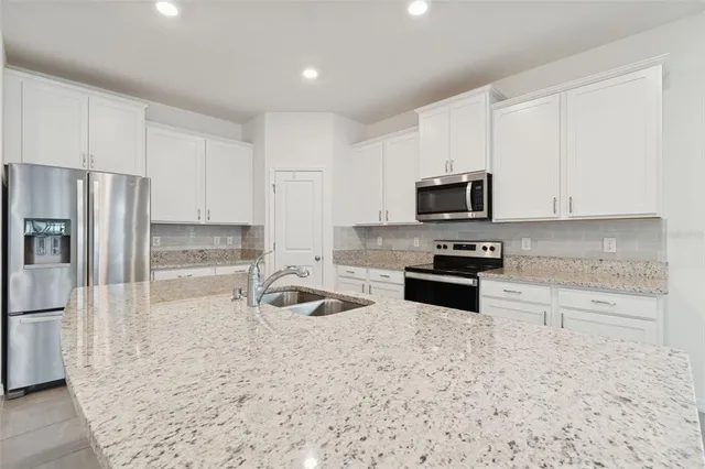 a kitchen with granite countertop white cabinets and white appliances