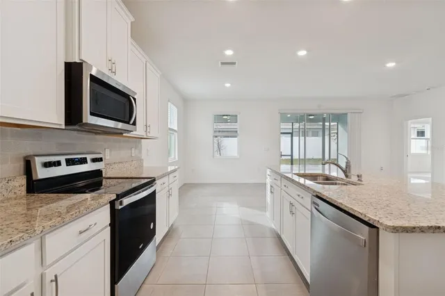 a kitchen with stainless steel appliances granite countertop a sink and dishwasher a stove top oven with white cabinets