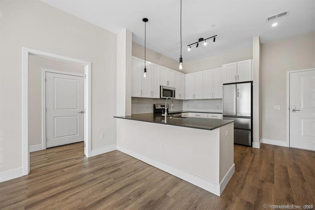 10 A Willard Road, Unit 456 Norwalk, CT 06851 - Photo 18 of 29 a kitchen with stainless steel appliances granite countertop a refrigerator a sink a stove and white cabinets with wooden floor