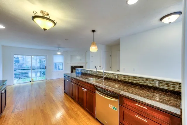 a kitchen with granite countertop a stove a sink and a wooden cabinets