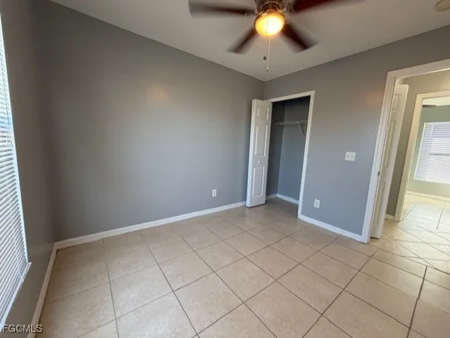 an empty room with closet and a chandelier fan